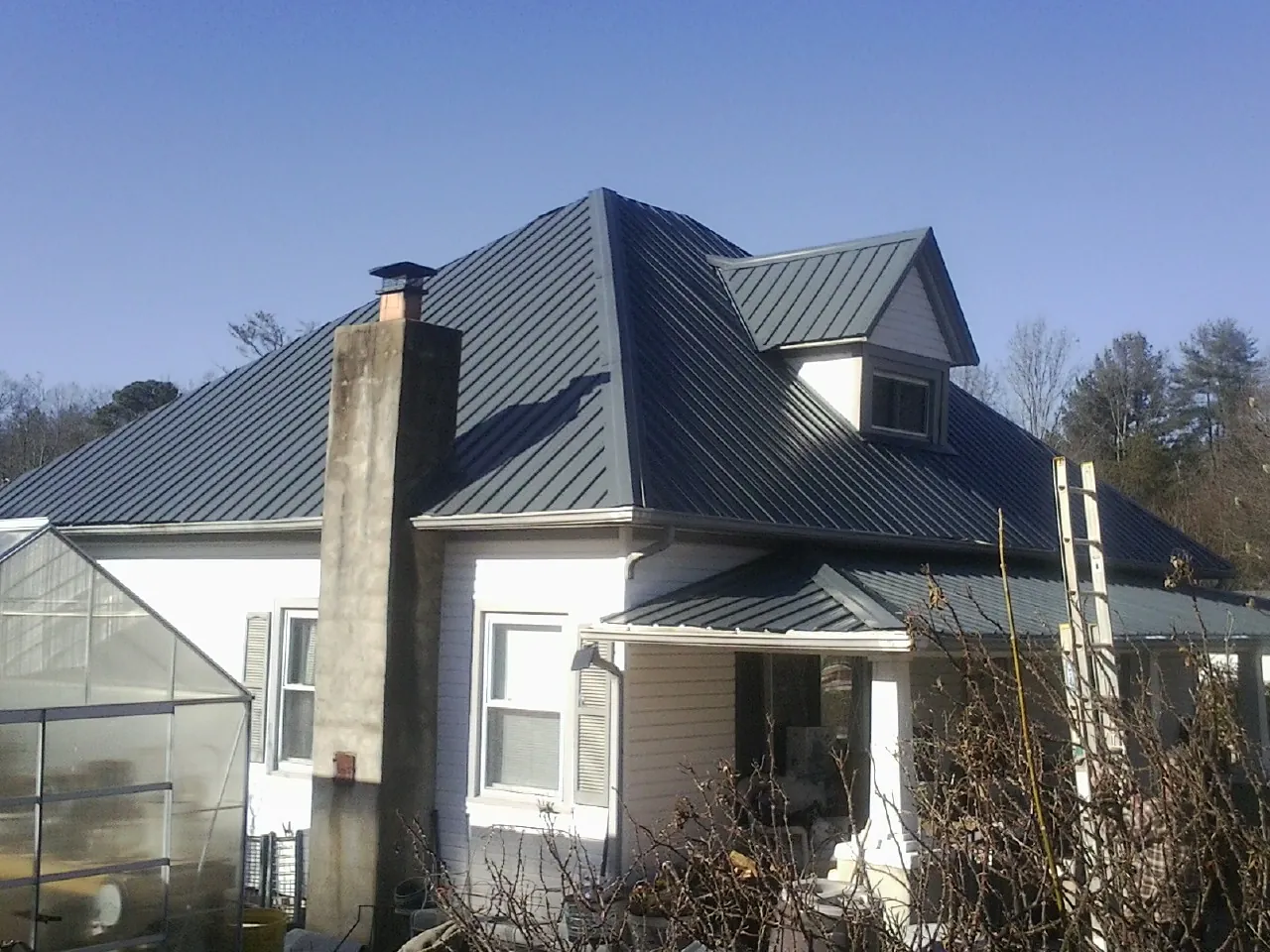 Dark blue standing seam metal roof on a white farmhouse with dormer — Slate & Tile Roof Repair by Roofing Brothers in South Lebanon