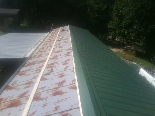 Old rusted panels beside newly installed green metal roofing — Wind Damage Roof Repair by Roofing Brothers in South Lebanon