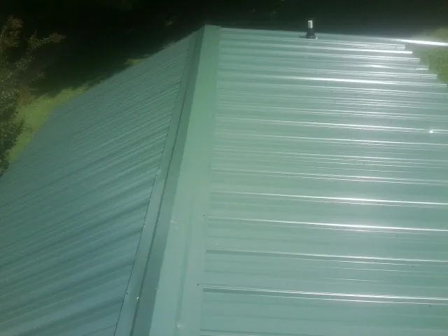 New green metal panels meeting at the ridge of a roof — Flat Roof Repair work by our crew in South Lebanon