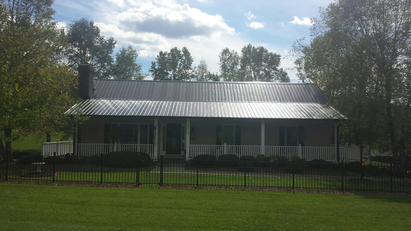 Gray metal roof on a brick ranch with a full width front porch — Gutter Guard Installation work by our crew in South Lebanon