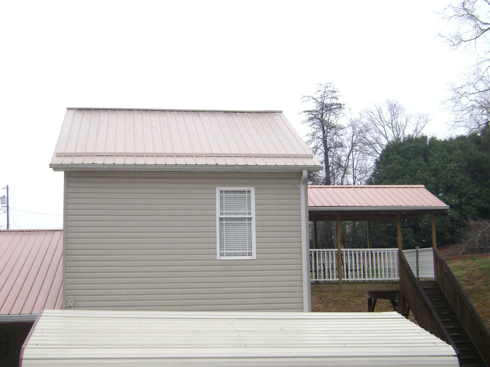 Tan metal roofs on a two story addition and attached porch, from a Roof Replacement job in South Lebanon