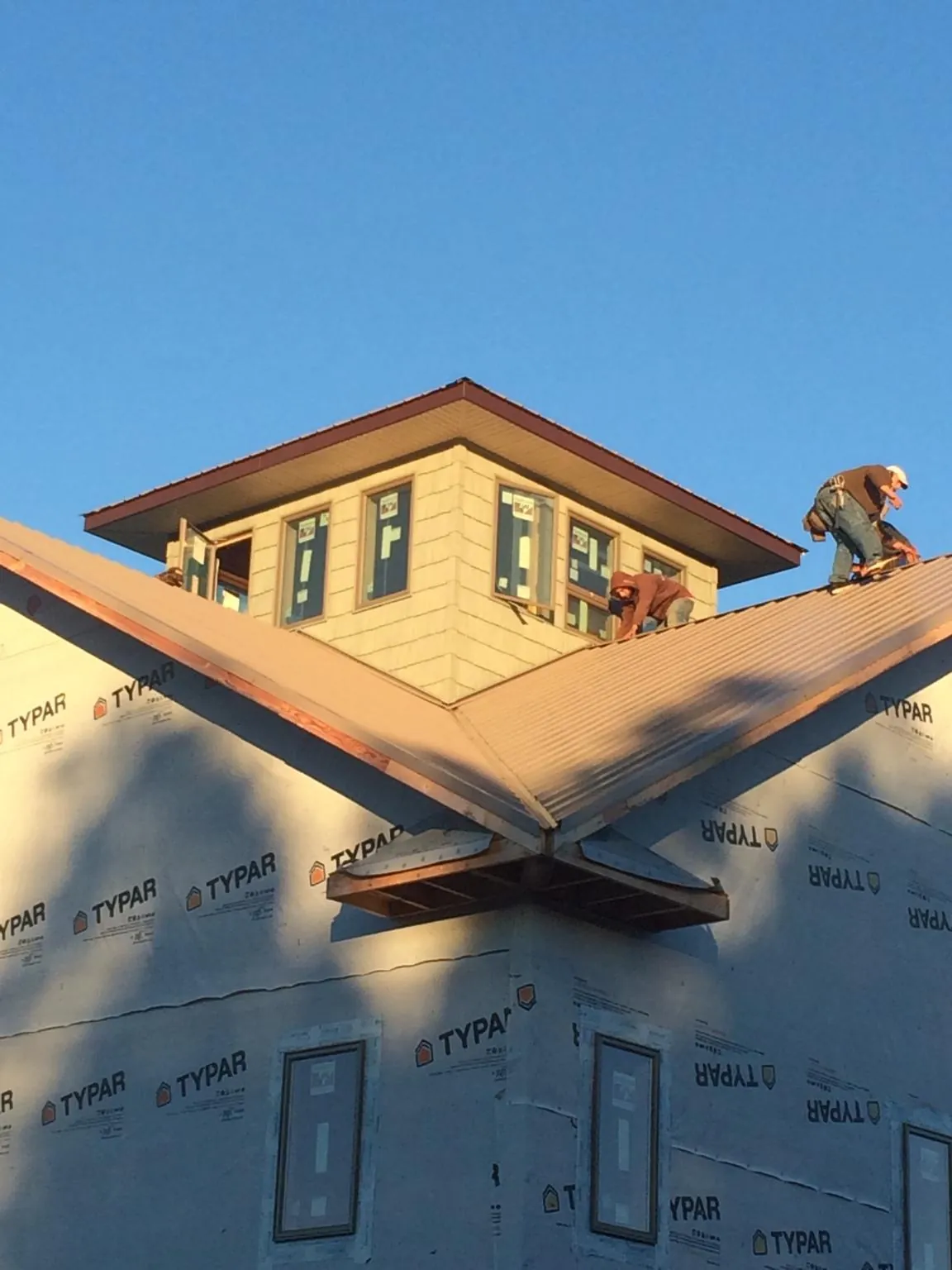 Roofers working around a rooftop cupola on a new metal roof at sunset — Roof Waterproofing in South Lebanon by Roofing Brothers